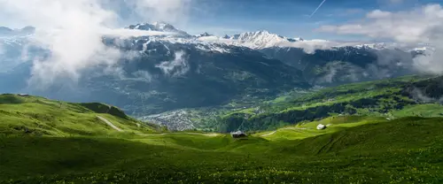 3840x1600 Ultrawide 自然风景 Wallpaper - Cloud-Wrapped Alpine Peaks Above a Green Valley with Cabins