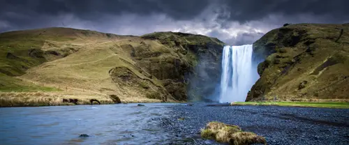 3840x1600 Ultrawide 自然风景 Wallpaper - 乌云下草坡峡谷瀑布与前景蓝灰色河流